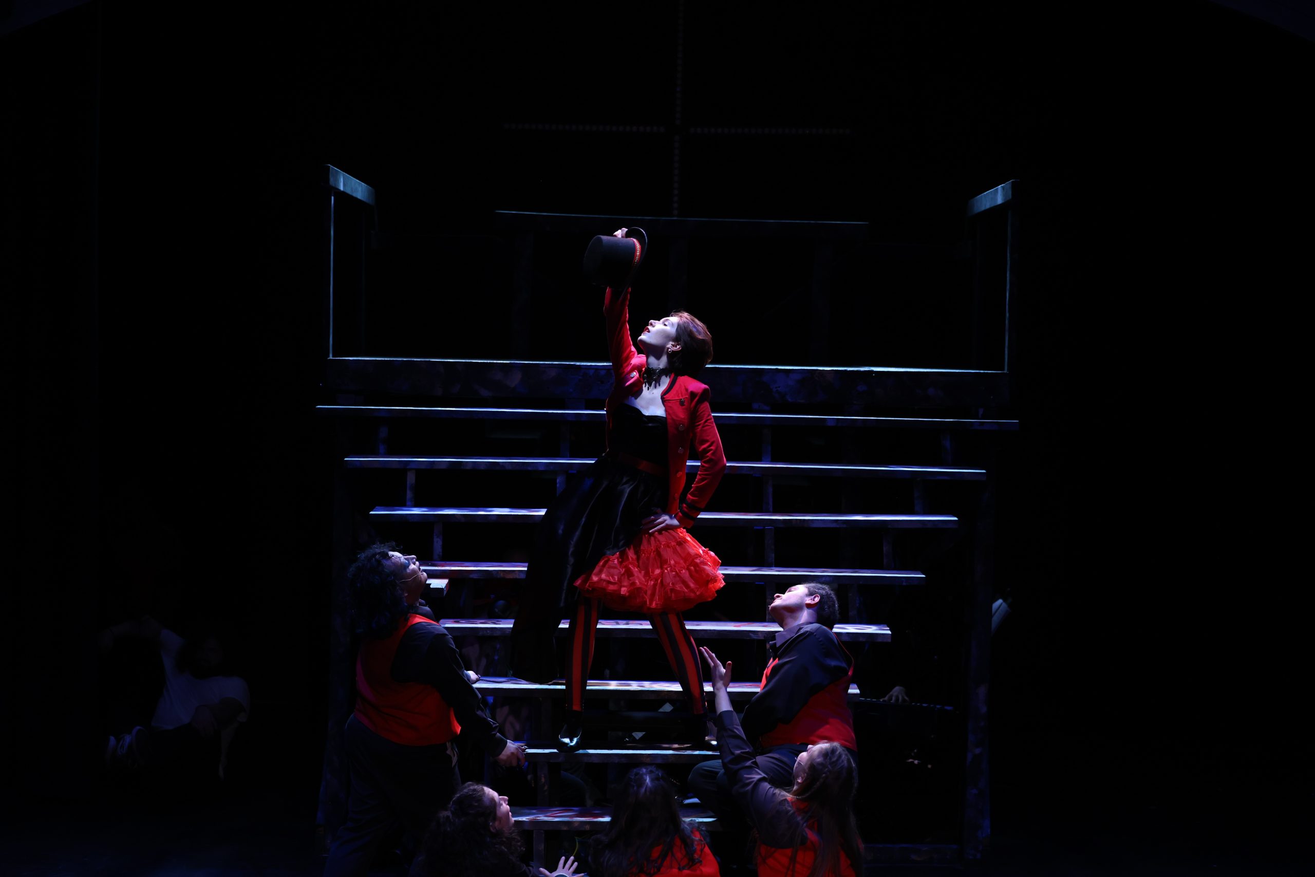 Dramatic lighting on a performer in an end pose after a musical number.