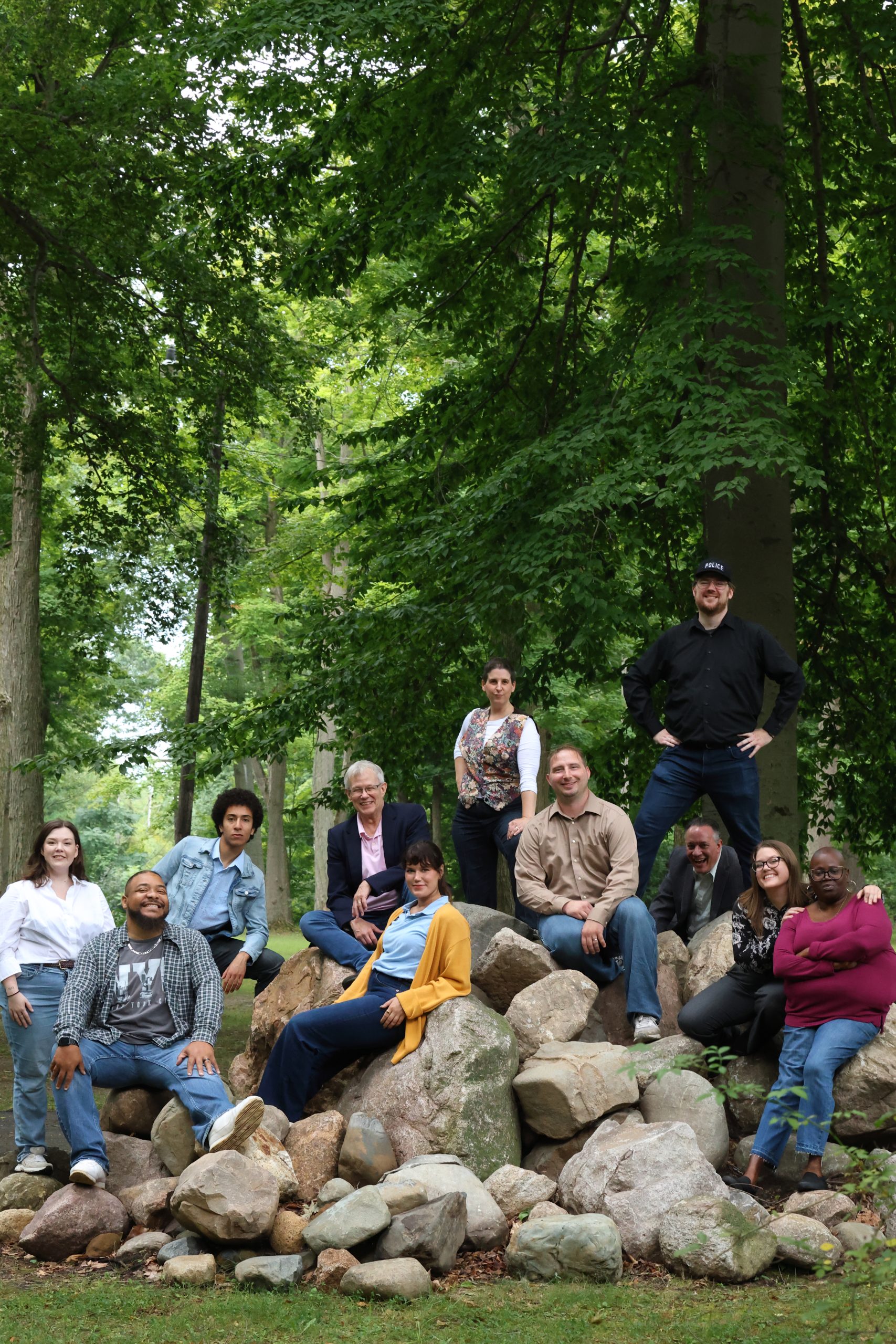 Group photo of the cast on large rocks in a forest
