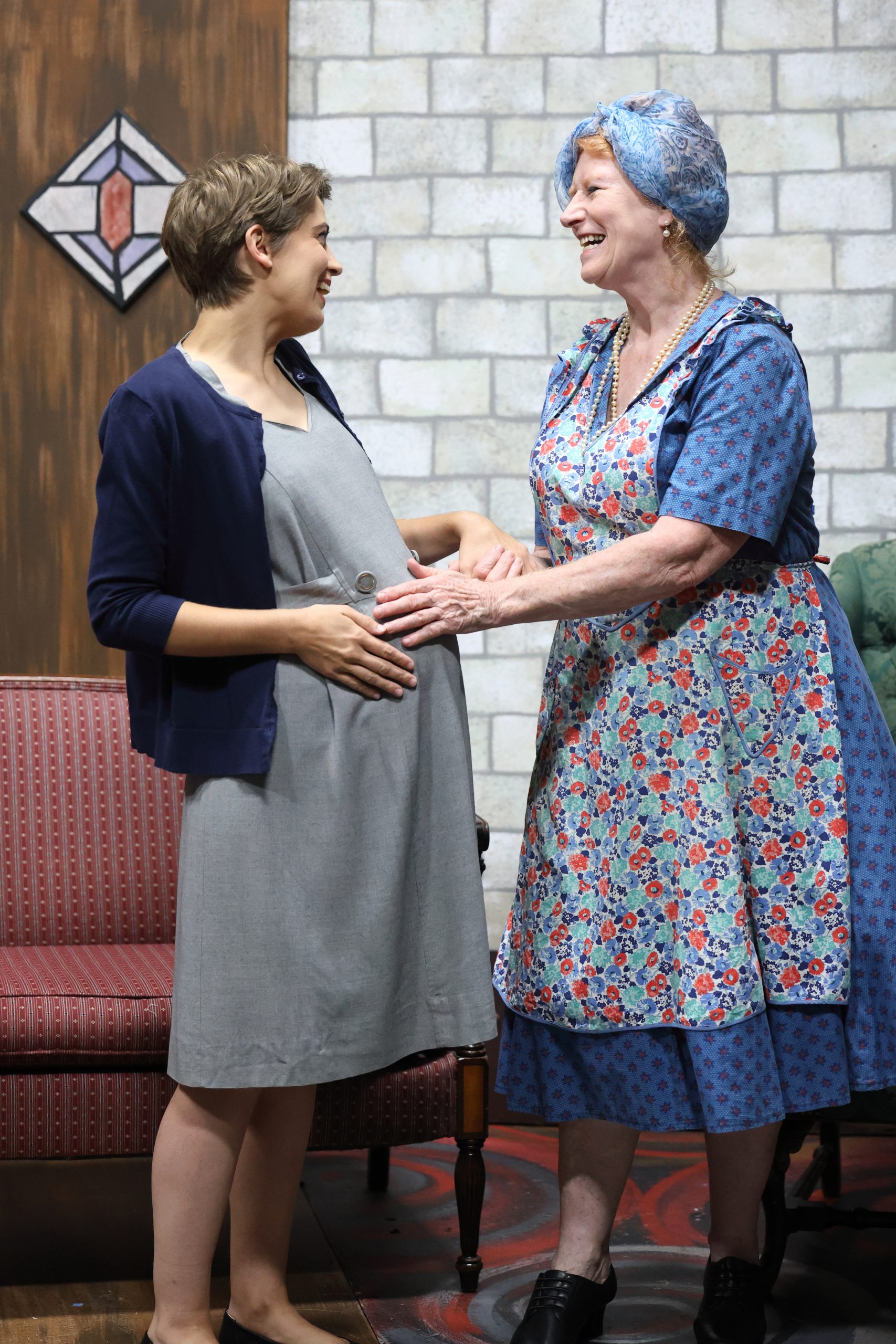 rehearsal photo of a pregnant woman and older woman, they are both smiling.