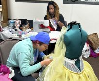 Costumer and assistant work on costume pieces.