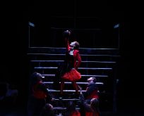 Dramatic lighting on a performer in an end pose after a musical number.