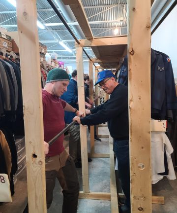 Volunteers put together clothing racks at the Costume Shop